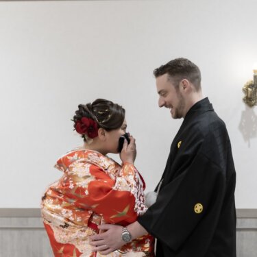 涙を拭く色打掛の花嫁を、腰に手を添えて見守る紋付袴の新郎。ファーストミートの和装前撮り