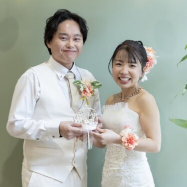 ミントグリーンの壁の前で、パールのリングピローを二人で持つ新郎新婦。小物を使ったスタジオフォト