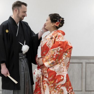 扇子を手にした新郎が色打掛の花嫁の頬にそっと触れる、やさしい和装フォトウェディングの一枚