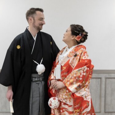 壁灯の前で見つめ合う紋付袴の新郎と鶴柄の赤い色打掛の花嫁。スタジオで撮る和装前撮り
