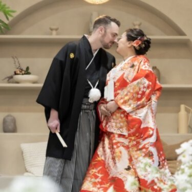 アーチの棚と竹の照明のセットで、額を寄せ合う紋付袴の新郎と赤い色打掛の花嫁の和装スタジオフォト