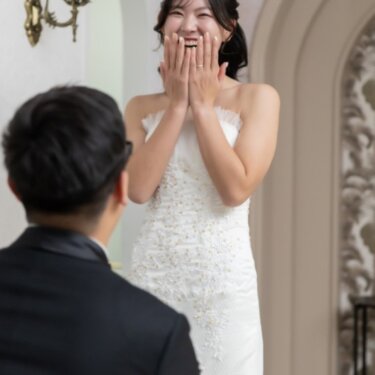両手で口元を覆って驚き喜ぶウェディングドレスの花嫁。プロポーズ演出で撮るスタジオフォト