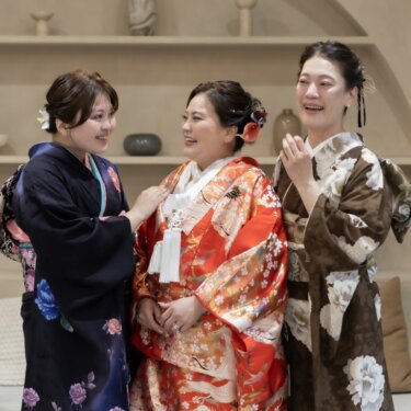 赤い色打掛の花嫁と、振袖・訪問着の家族の女性が笑い合う和やかな和装前撮りのスナップ