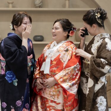 涙ぐむ家族と、ほほえむ赤い色打掛の花嫁。支度後の対面を写したフォトウェディングの家族写真