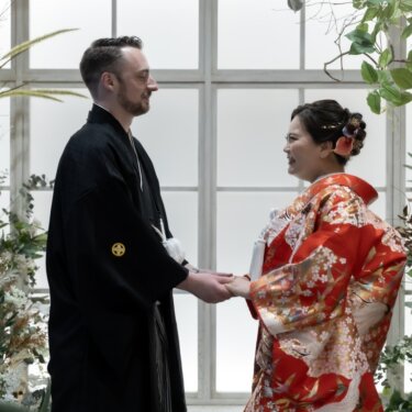 花のアーチと大きな窓のセットで手を取り合う、紋付袴の新郎と色打掛の花嫁。スタジオで撮る和装前撮り