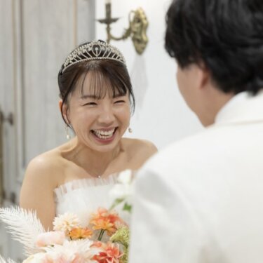 新郎の後ろ姿越しに写した、ティアラをつけて大笑いする花嫁のアップ。ファーストミートの結婚写真