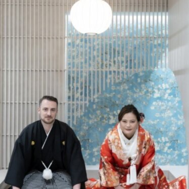 丸い和紙の照明と格子の和モダンなセットで、並んで正座する紋付袴の新郎と色打掛の花嫁のスタジオフォト