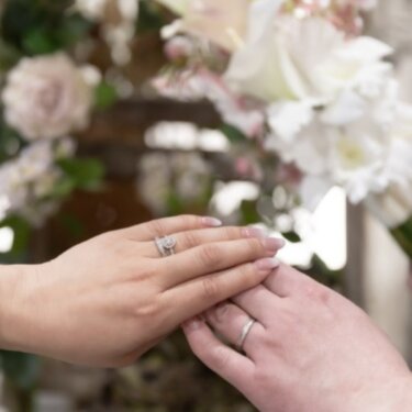 桜の花を背景に重ねた二人の手と、光る指輪のクローズアップ。前撮りで残す手元のカット