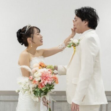 花嫁が新郎のほおを手でつまむ、遊び心あるワンシーン。ティアラとブーケの花嫁のスタジオフォト