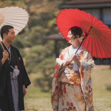 白と朱赤の和傘をそれぞれ差し、見つめ合う羽織袴の新郎と色打掛の花嫁。三渓園の庭園で撮る和装前撮り