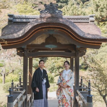 三渓園の唐破風の東屋の下に並んで立つ、黒紋付袴の新郎と色打掛の花嫁。伝統的な意匠が印象的な和装前撮り
