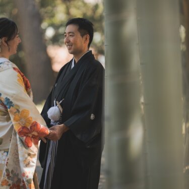 竹の間からのぞくように写した、手をつなぎ見つめ合う新郎新婦。竹林の緑がやさしい和装フォトウェディング