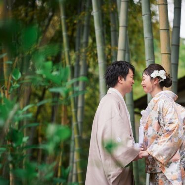 三渓園の竹林で手をつなぎ、見つめ合ってほほえむ色打掛の花嫁と羽織袴の新郎。穏やかな和装前撮り