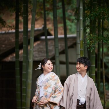 竹林の中で同じ方向を見て大笑いする、色打掛の花嫁と羽織袴の新郎。笑顔がはじける和装前撮り
