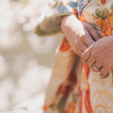 三溪園にて、桜をぼかした背景に、指輪が輝く花嫁の手元のアップ。花柄の色打掛が映えるディテールカットの結婚写真
