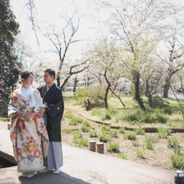 しだれ桜の下の木道で、新郎が花嫁の肩に手を添えて寄り添う開放的な和装フォトウェディング