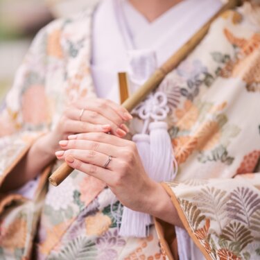 三溪園にて、和傘の柄を持つ花嫁の手元と、色鮮やかな色打掛の刺繍を写したクローズアップ。指輪が光る和装フォトウェディング