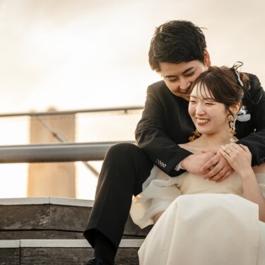 大さん橋の階段状デッキで、後ろから花嫁を抱きしめて大笑いする新郎。カラーで残す自然体のウェディングフォト