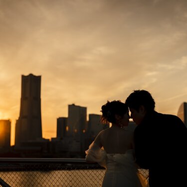みなとみらいのランドマークタワーに沈む夕日を背景に、額を寄せ合う新郎新婦のシルエット。横浜らしい夕景の前撮り