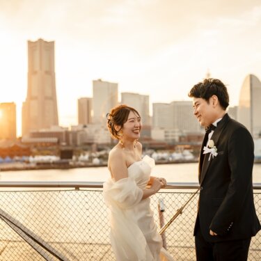 夕日に染まるランドマークタワーとみなとみらいの街並みを背に、大笑いする新郎新婦の前撮り