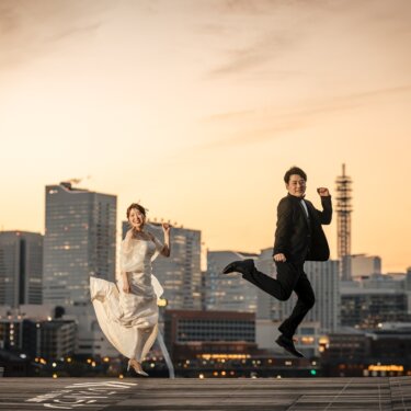 ライトアップされたみなとみらいの街並みを背に、大きくジャンプする新郎新婦の躍動感あふれる前撮り