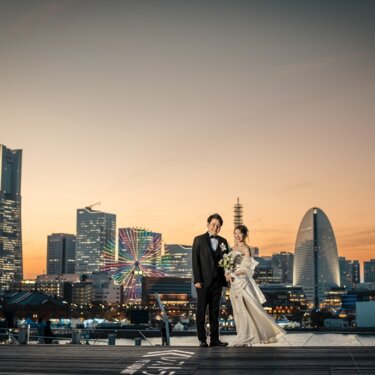ランドマークタワーとカラフルな観覧車の夜景を望む大さん橋のデッキで、寄り添う新郎新婦の前撮り