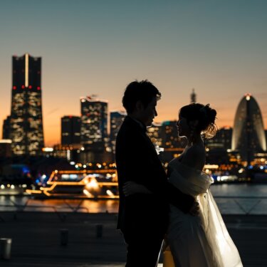 大さん橋にて、ランドマークタワーの夜景を望む港で見つめ合う新郎新婦。イルミネーションの船も見える夜の前撮り