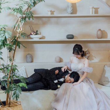 アーチ状の飾り棚とペンダントライトのスタジオで、花嫁の膝枕で眠る新郎。遊び心のある洋装前撮りのポーズ