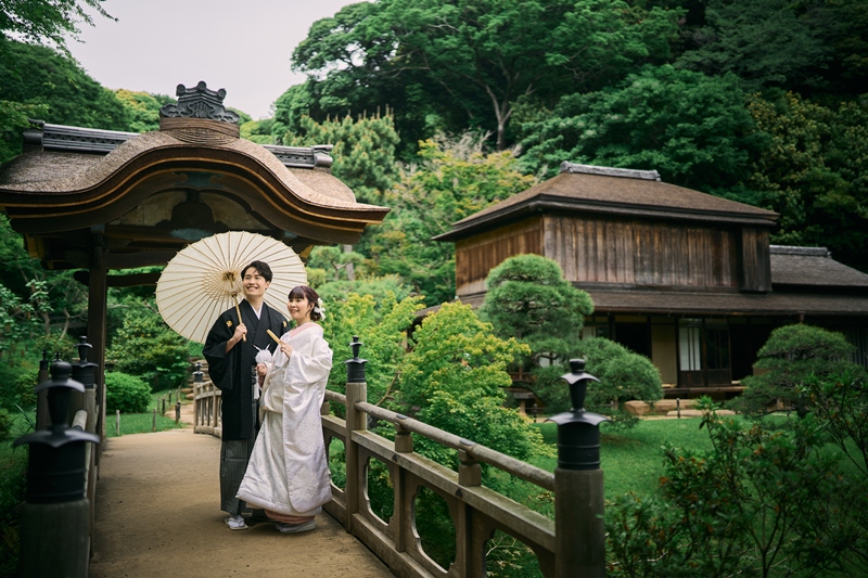 三重塔を背景に橋の上で和傘を差す新郎新婦