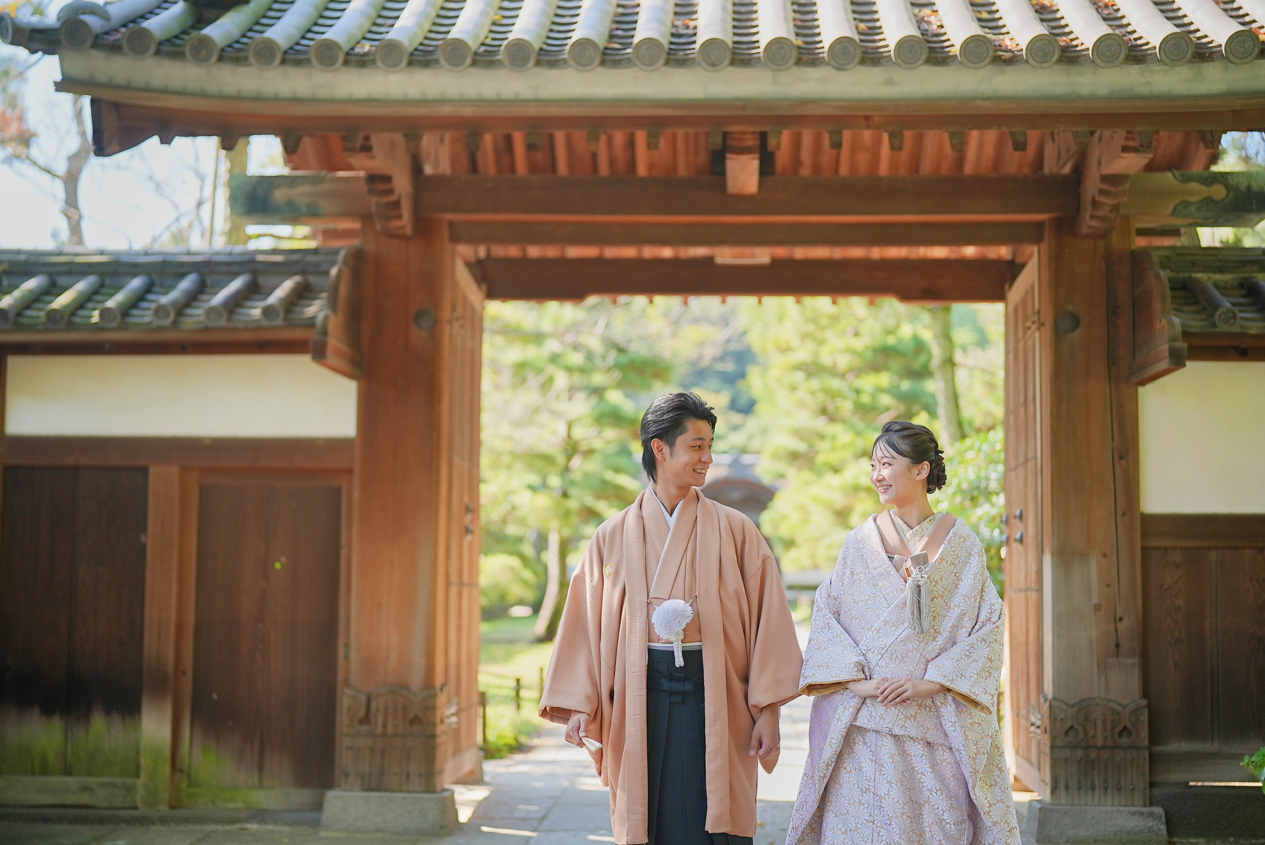 三溪園の歴史ある門をくぐる和装の新郎新婦