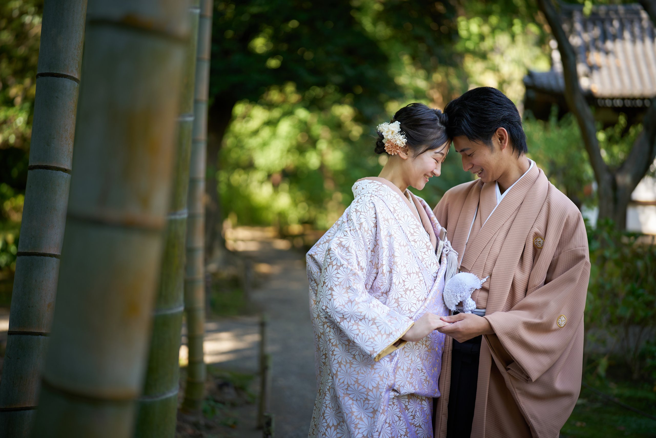 竹林の中で寄り添い笑い合う和装の新郎新婦