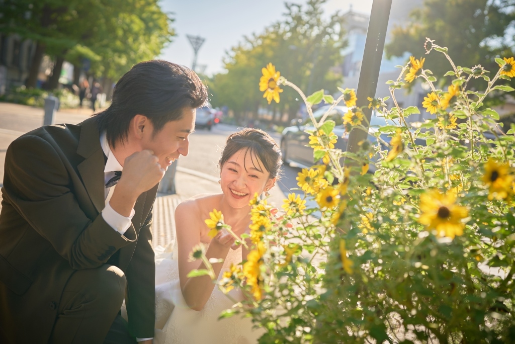 道端の花を見つけて笑い合う前撮りカット
