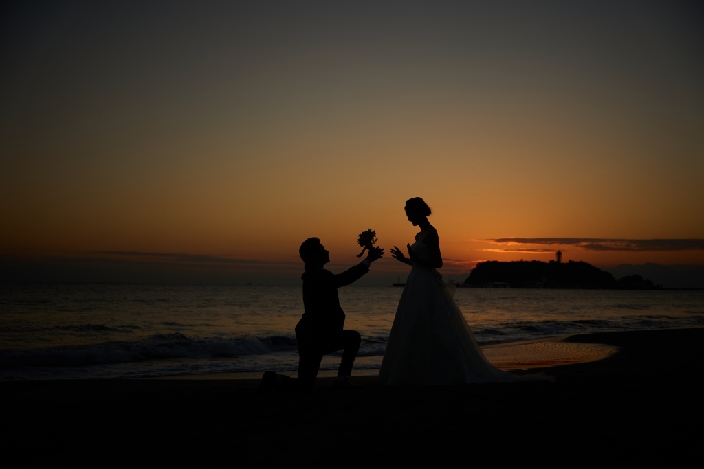 花束を受け取りながら微笑む新婦とプロポーズする新郎