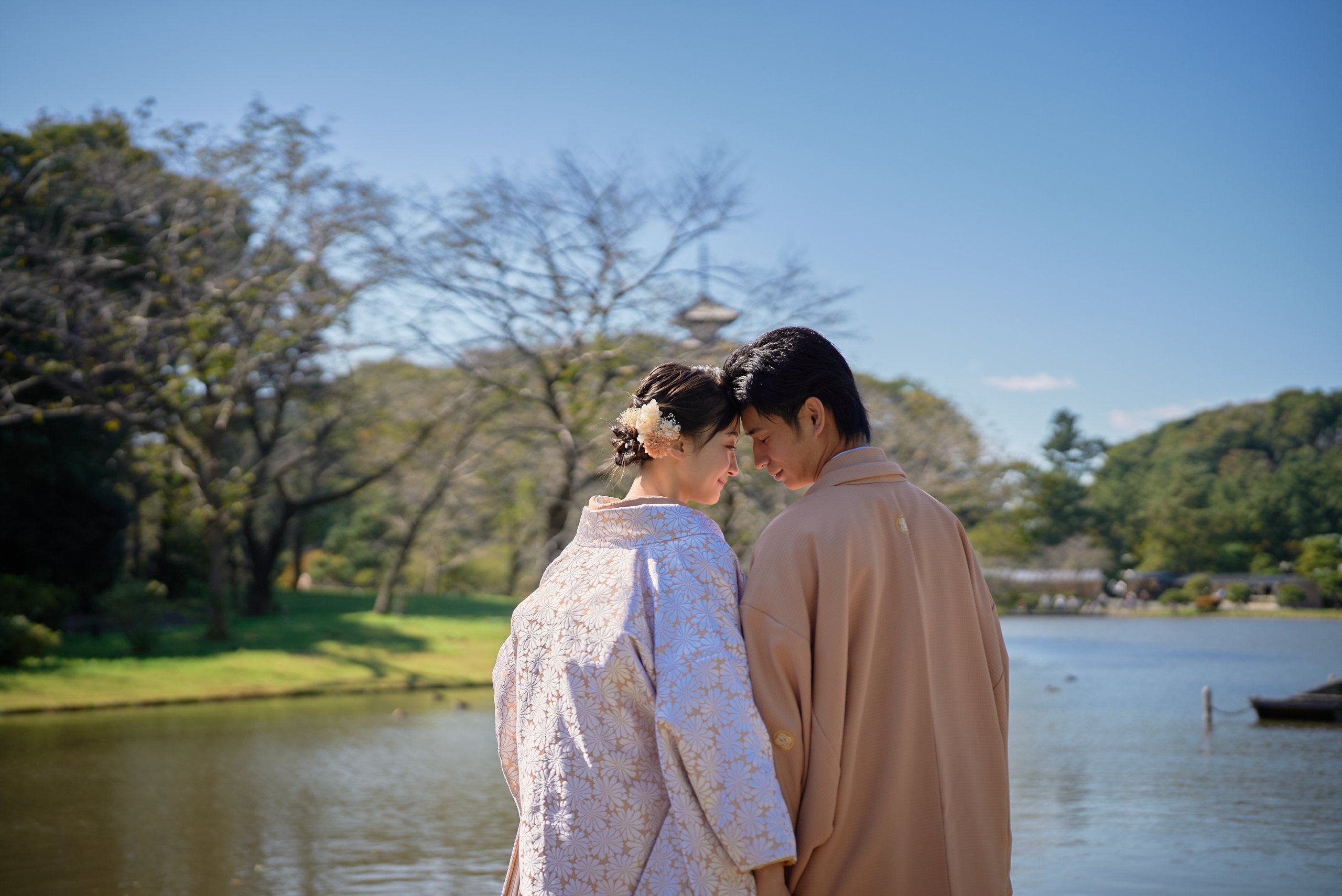 池を背景に寄り添う和装の新郎新婦の後ろ姿