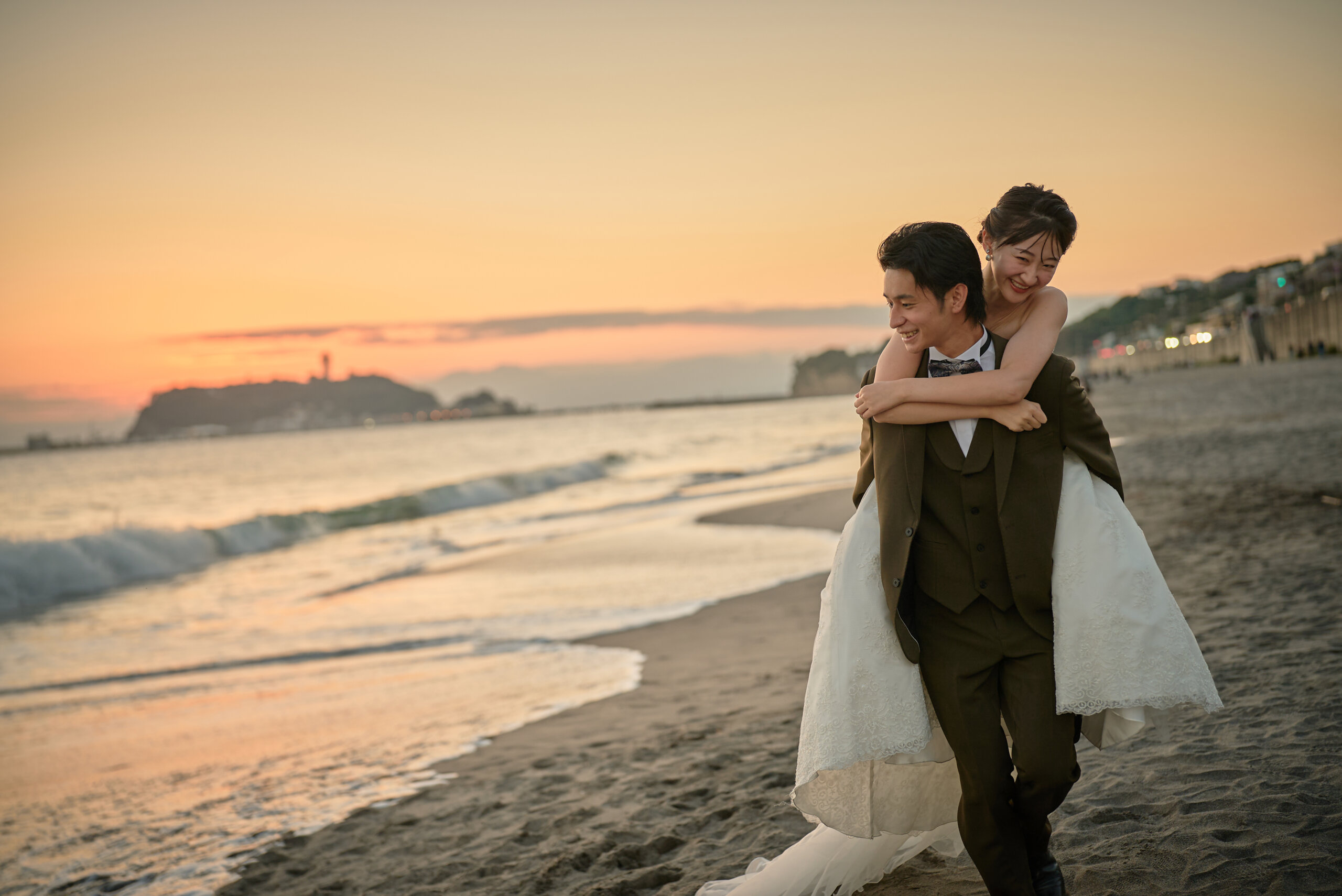 夕焼けの七里ヶ浜に並んで立つ新郎新婦の遠景