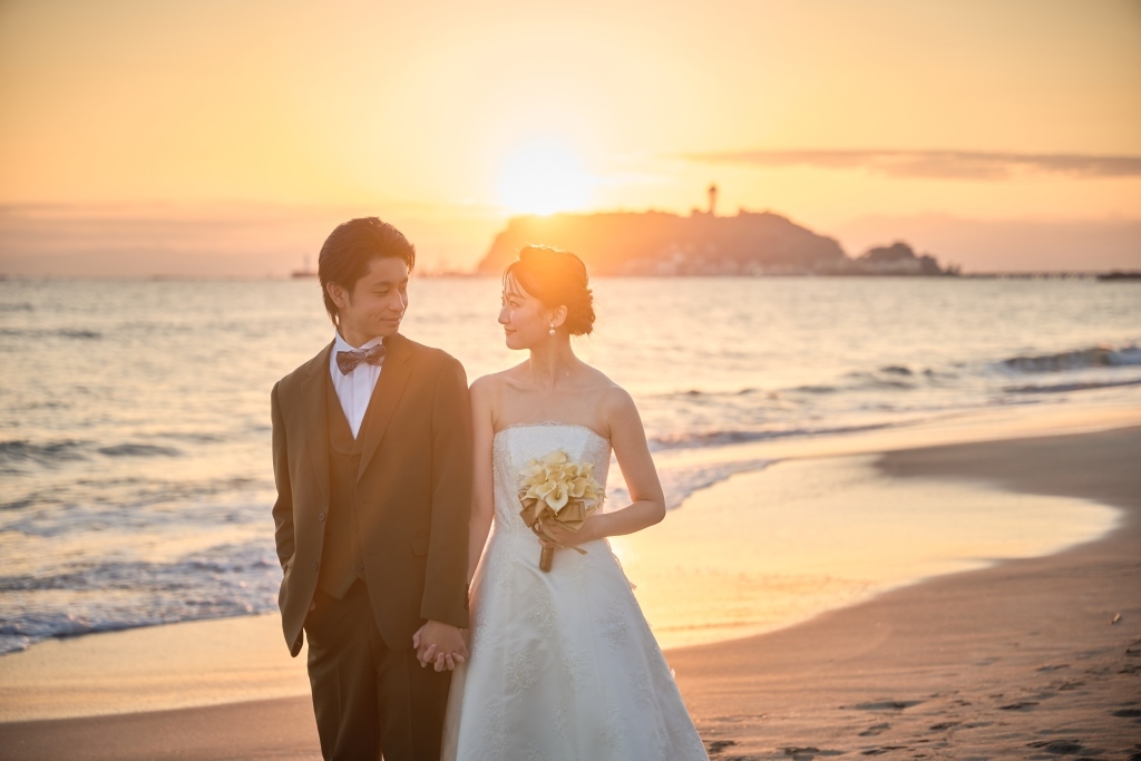夕焼けの七里ヶ浜に並んで立つ新郎新婦の遠景