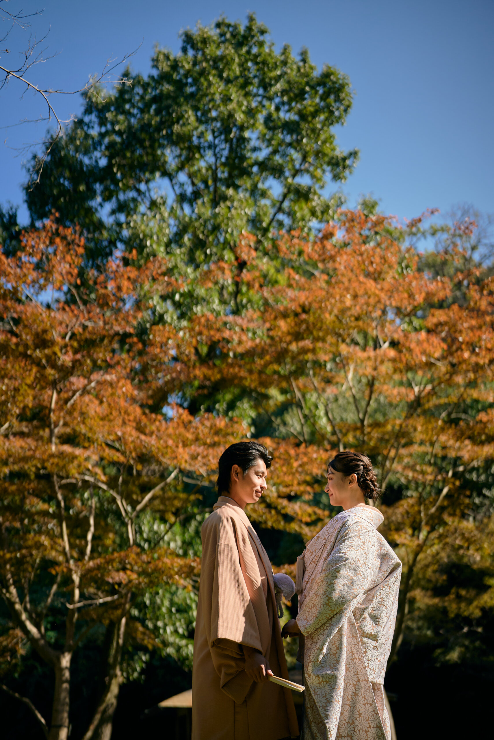 久良岐公園の紅葉に彩られた石畳の小径を手をつないで歩く新郎新婦
