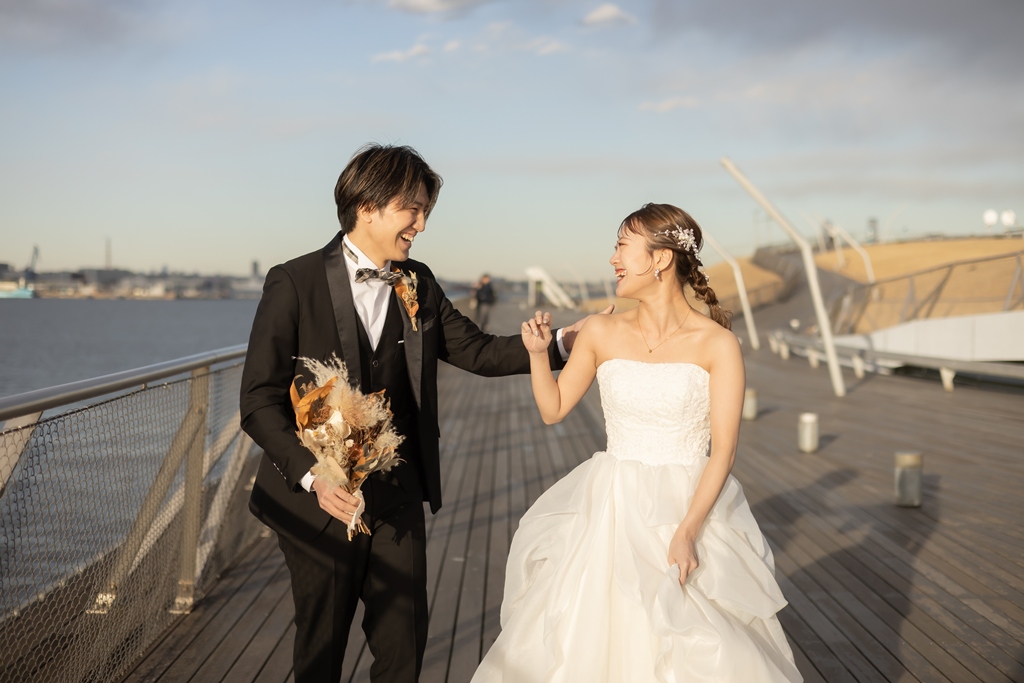 日中の大さん橋でブーケを持ち笑い合いながら歩く新郎新婦