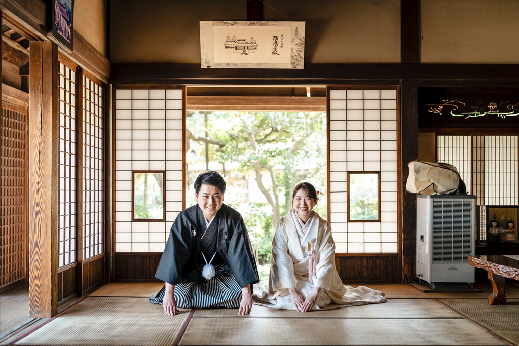 畳の和室で正座して微笑む和装の新郎新婦
