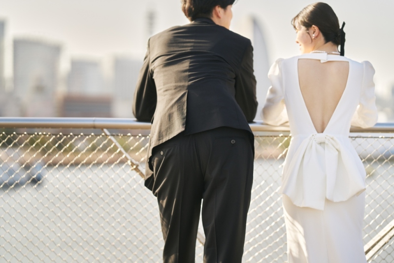背中が大きく開いたバックデザインのドレスで景色を眺める新郎新婦の後ろ姿