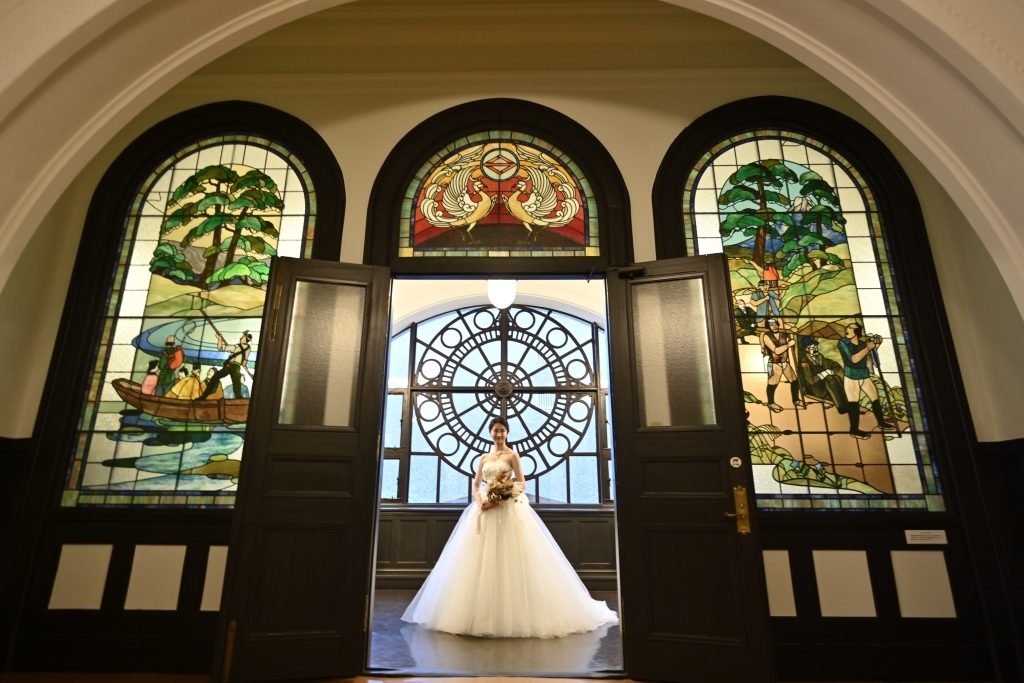 色鮮やかなステンドグラスを背景に佇む白いドレスの新婦