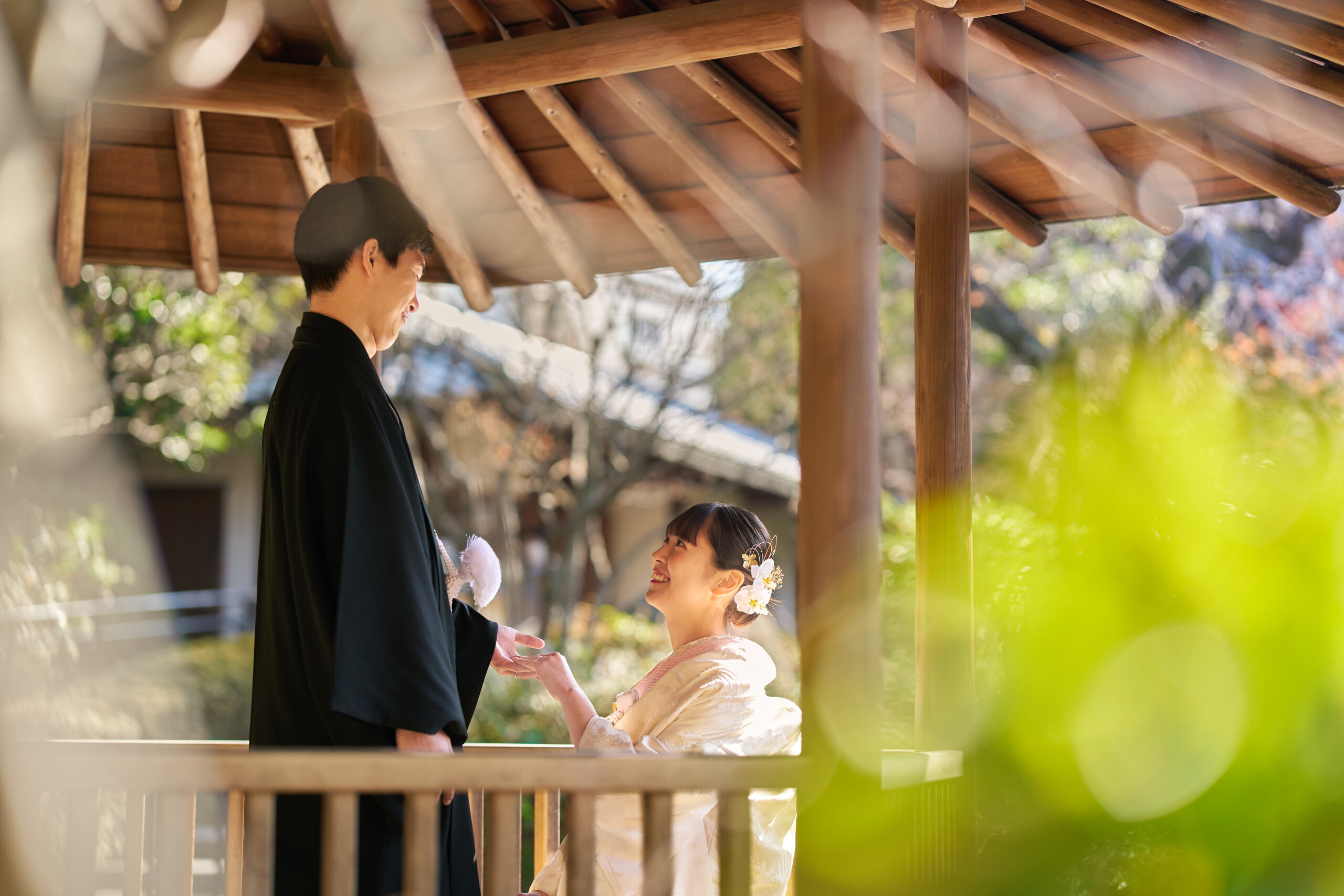 木漏れ日の中、寄り添いながら空を見上げる新郎新婦