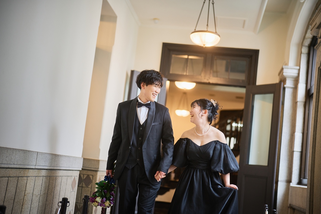 夕暮れの横浜市開港記念会館前で振り返る新婦とその後ろに佇む新郎