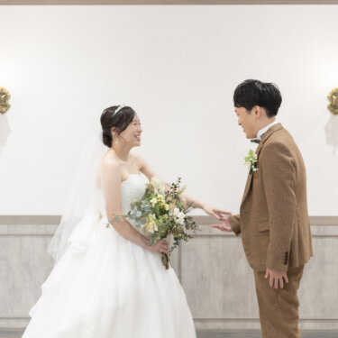 振り向いた新郎と笑顔で向き合う花嫁。ファーストミートでドレス姿を初めて見せる瞬間の結婚写真