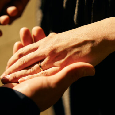 重ねた新郎新婦の手元のアップ。結婚指輪が夕方の光に浮かび上がる洋装前撮りのディテールカット