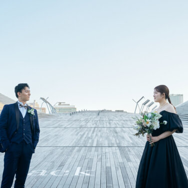 大さん橋のデッキに向かい合って立つタキシードの新郎とブーケを持つ花嫁。左右対称の構図が印象的な洋装ロケーションフォト