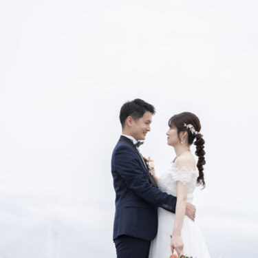 横浜ベイブリッジを背に見つめ合う新郎と、編み込みのヘアアレンジにドライフラワーのブーケを合わせた花嫁。大さん橋で撮る前撮り