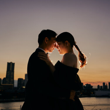 ランドマークタワーの夕焼けを背景におでこを寄せ合う新郎新婦のシルエット。大さん橋から撮るマジックアワーのロケーションフォト