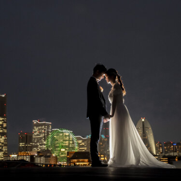 みなとみらいの夜景を背に額を寄せ合う新郎新婦のシルエット。大さん橋で撮る夜の洋装前撮り