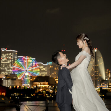 観覧車の夜景を背に、新郎が花嫁を高く抱き上げる大さん橋のナイトフォト。横浜みなとみらいの夜の前撮り
